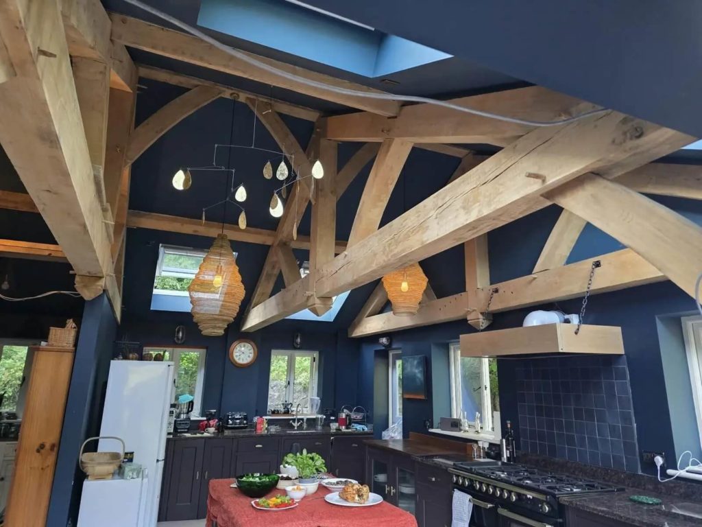 Traditional oak framed kitchen extension in a restored North Wales water mill with exposed oak beams and vaulted ceiling.
